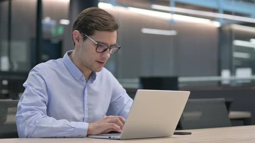 Frustrated Young Adult Man Working on Laptop in Office