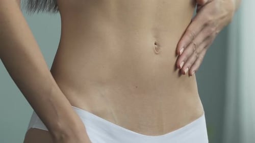 Reflexión de mujer en forma en ropa interior tirando en el estómago, programa de pérdida