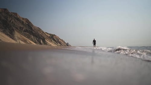 Hombre caminando por la playa cuando llega la marea