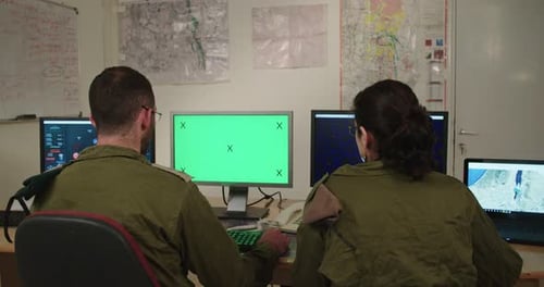 Israeli soldiers in a military command and control room looking at screens