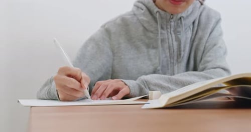 Student Writes on Paper with Pen Indoors