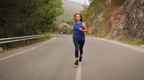 Woman Running on Road in Mountainous Landscape