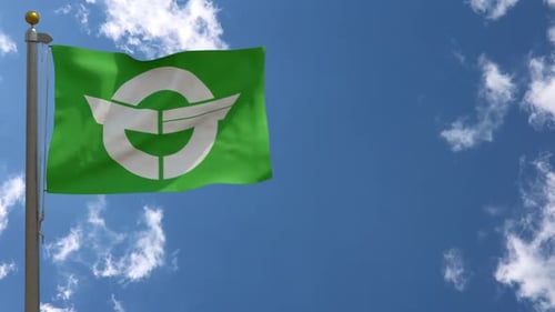 Green Flag with Abstract White Symbol Waving Against Blue Sky