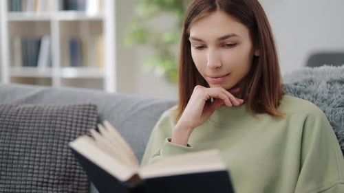 Young Woman Reading Book on Cozy Couch