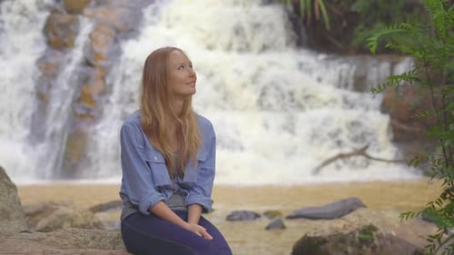 Woman Relaxing by Scenic Waterfall in Nature