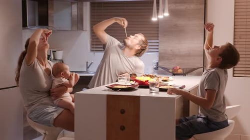 Family Enjoys Eating Spaghetti in Kitchen