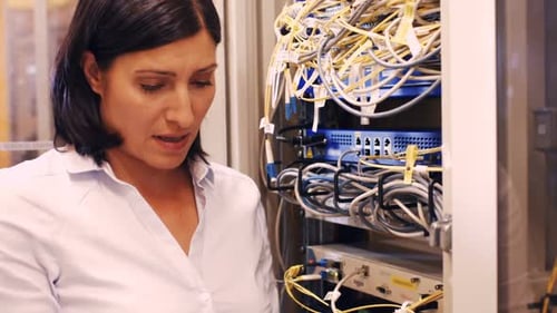Woman Inspecting Server Rack with Tablet