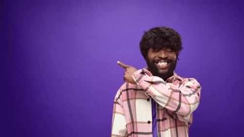 Young Man Points Energetically on Purple Background