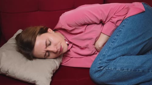 Woman Lying on Couch with Stomach Pain