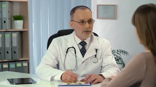 Attentive Therapist in Eyeglasses Prescribing Medicine to Patient in Hospital