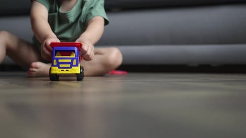 Unrecognizable Baby Boy Kid Driving Plastic Car Truck Camera Wooden Floor Home