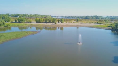 Springbrunnen im See auf einer Wiese vor blauem Himmel, Ansicht von oben