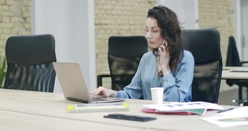 Woman Talking on Phone and Using Laptop in Office