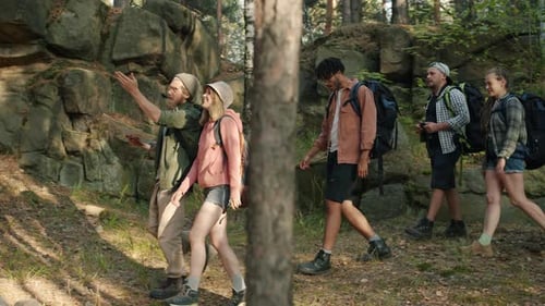 Side View of Tourists Friends Walking in Forest on Summer Day Holding Map Talking