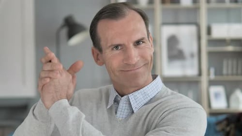 Man Smiling and Clapping Hands Together Indoors
