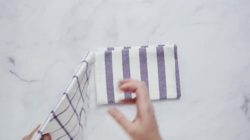 Folding a Clean Kitchen Towel on Marble Countertop