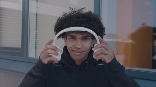 Smiling Young Adult Puts on Headphones