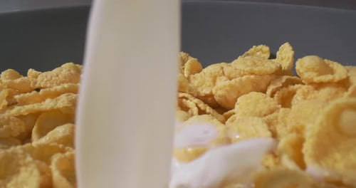 Milk Being Poured onto Cornflakes Cereal in Bowl