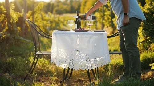 Ein Mann gießt Wein in ein Glas und bereitet sich auf ein romantisches Abendessen in der Natur vor