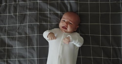 Crying Infant Lying on Gray Plaid Blanket