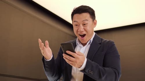 Excited Man Receives Positive News on Smartphone