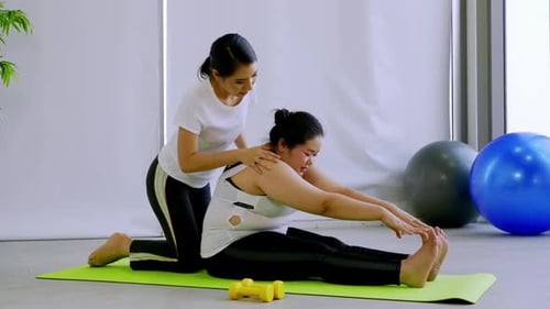 Trainer Coaching Woman in Stretching Exercise Indoors