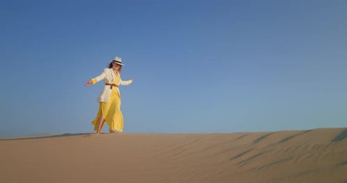 Young Woman Walking Barefoot on Top of Sand Dune in Desert