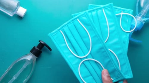 Man Hand Putting Surgical Masks on Green Background