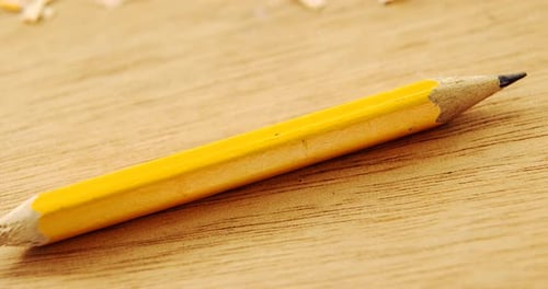 Broken yellow pencil and sharpener on wooden background