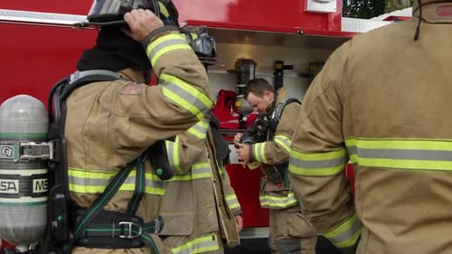 Firefighters Preparing Equipment Next to Truck