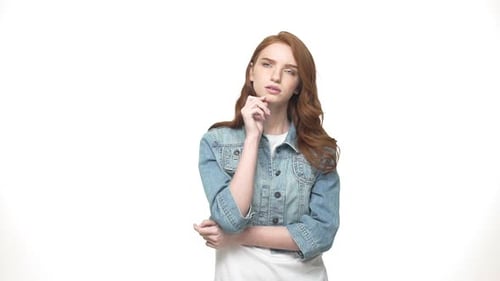 Fröhliches Mädchen denkt auf grauem Hintergrund. Porträt einer lässigen, glücklichen, wunderenden Frau in Denim