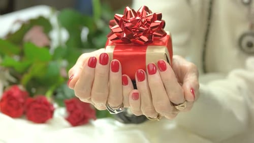 Hands Presenting Gift with Red Bow and Roses