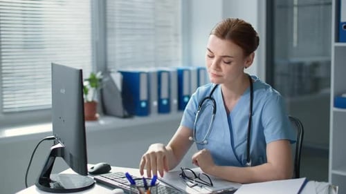 Tired Healthcare Worker at Computer in Bright Office