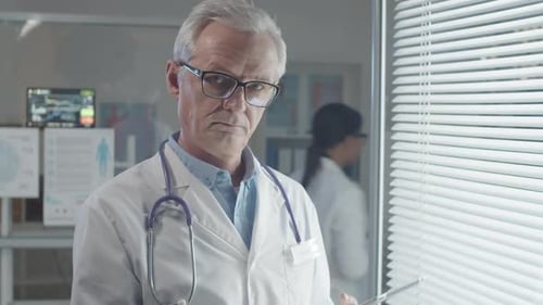 Thoughtful Doctor Holding Tablet in Modern Hospital