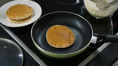 Golden Pancakes Cooking in a Pan on the Stove