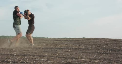 Two Brisk Fighters Training Arm and Legs' Hits Among Soil Field with Dust