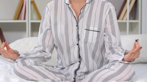 Woman Meditating in Pajamas on Bed at Home