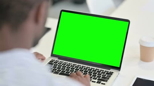 Rear View of African Man Using Laptop with Green Chroma Key Screen