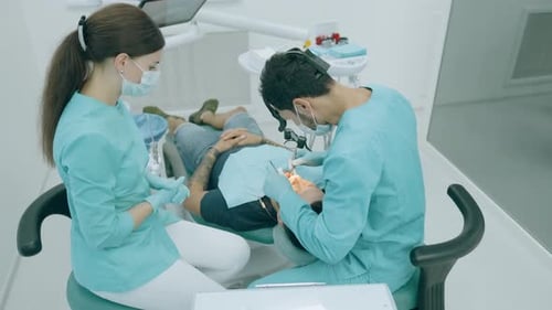 Dentist with Nurse and Patient in Dentist Office. A Patient Getting Dental Treatment at Dental