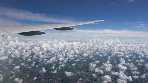 Das Flugzeug fliegt im blauen Himmel. Weiße Wolken und Stadt unter den Fittichen eines Flugzeugs