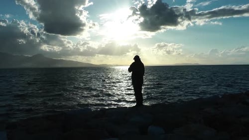 Man on Edge of Sea Water and Birds Feed