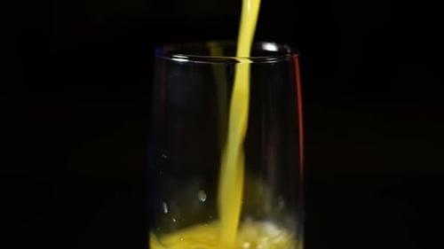 Yellow Juice Pouring into Glass on Black