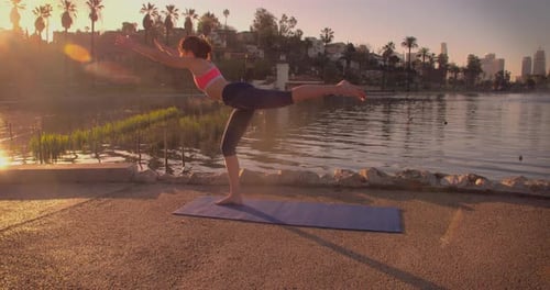 Femme faisant du yoga dans le parc à l'aube