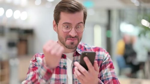 Young Adult Cheering While Using Smartphone