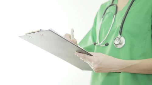 Medical Professional Writes on Clipboard in Green Scrubs