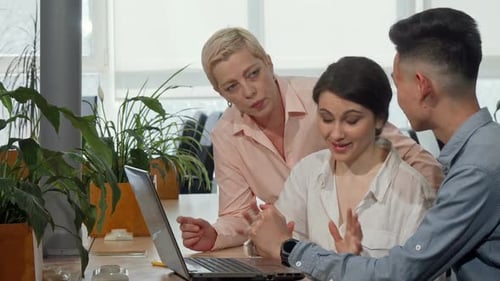 Team Collaboration Around Laptop in Bright Office