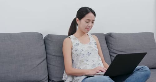 Woman Uses Laptop While Sitting on Couch at Home