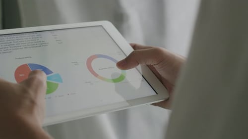 Empresário de close-up usando tablet examinando relatórios financeiros e analisando o crescimento dos negócios.