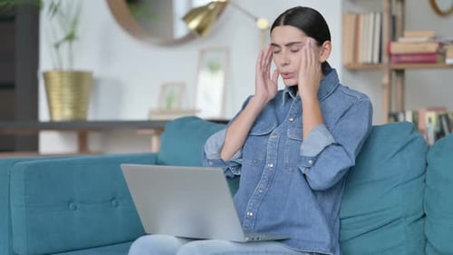 Woman Typing on Laptop at Home with Headache
