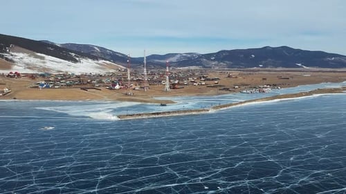Aerial Perspective View of Snow Covered Frozen Baikal Lake Surface with Settlement on Coast From